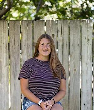 Young woman in front of wooden fence